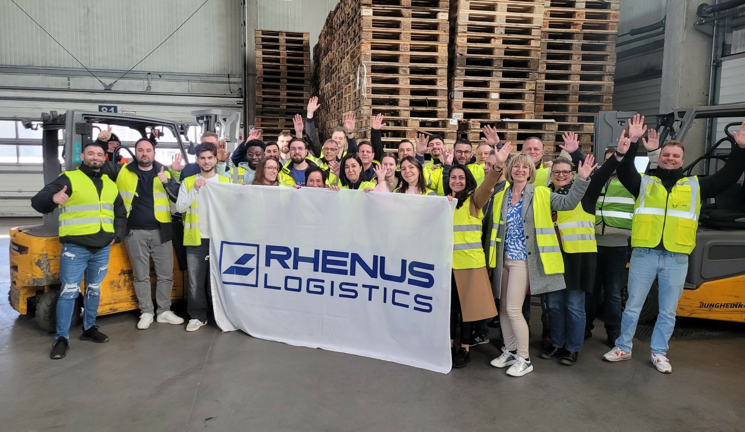Eine Gruppe Menschen hält ein Transparent mit dem Rhenus-Logo hoch.